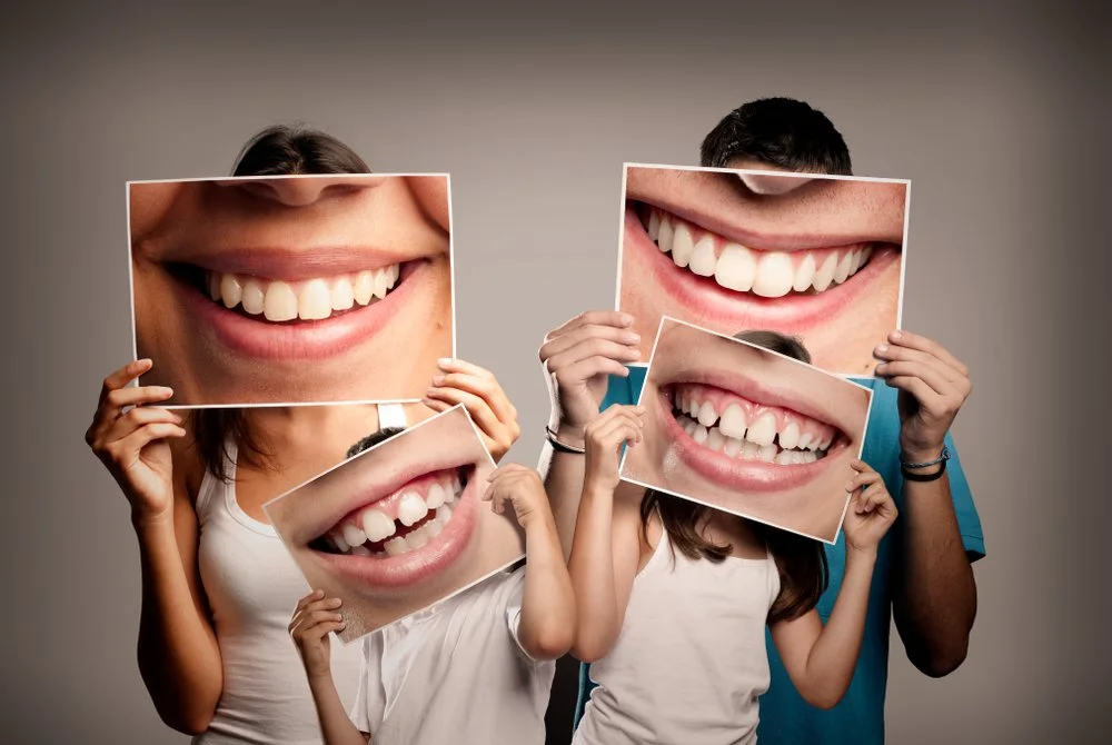 A family holding up photos of their smiles